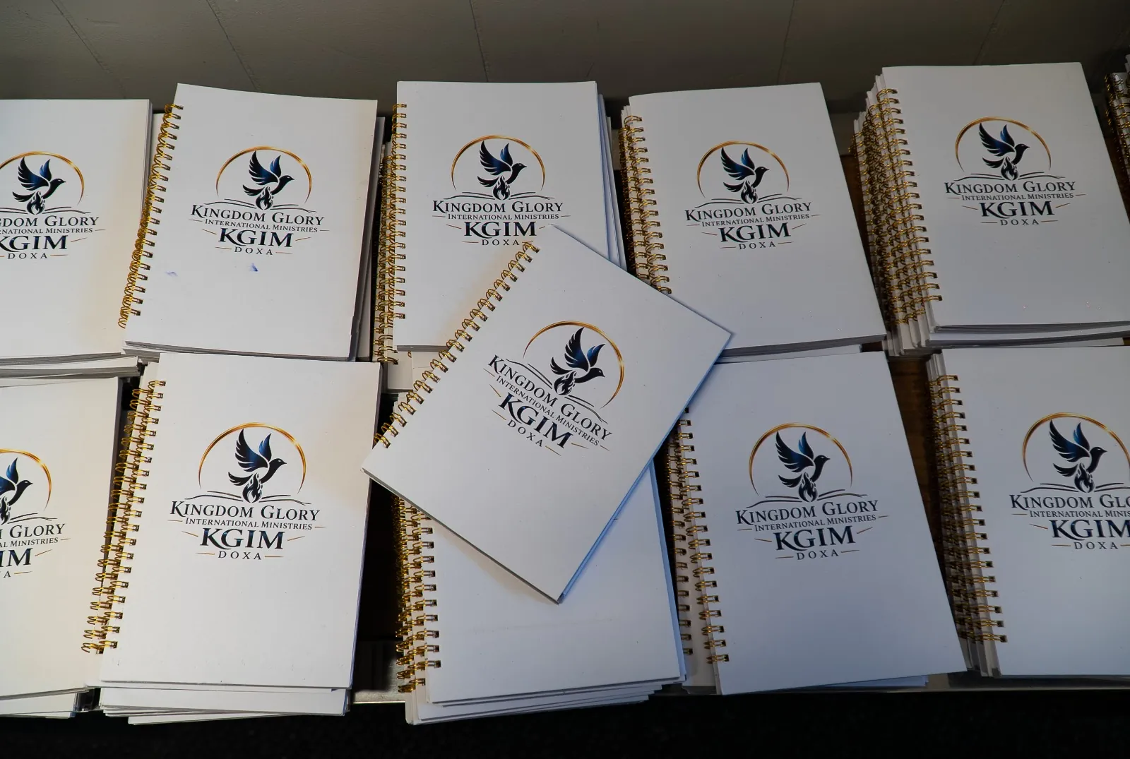 Stacks of notebooks bearing the Kingdom Glory International Ministries logo
